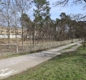 Ścieżka dla pieszych i rowerzystów, obok ogrodzenie; teren przy ul. Piaskowej